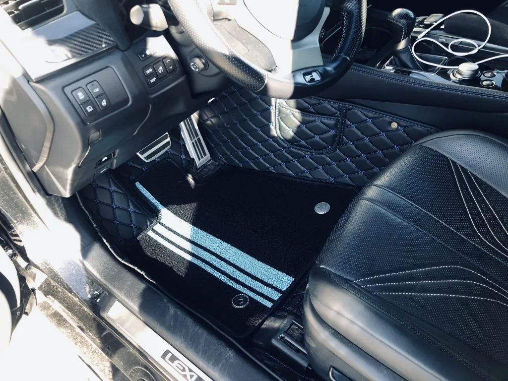 Black quilted leather car floor mats with blue stitching and striped carpet insert in a Lexus GS