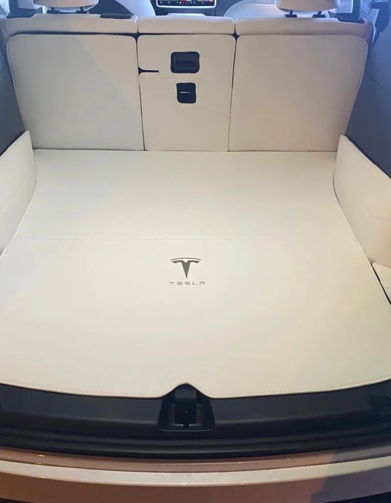 White leather trunk liner with Tesla logo in a Tesla cargo area